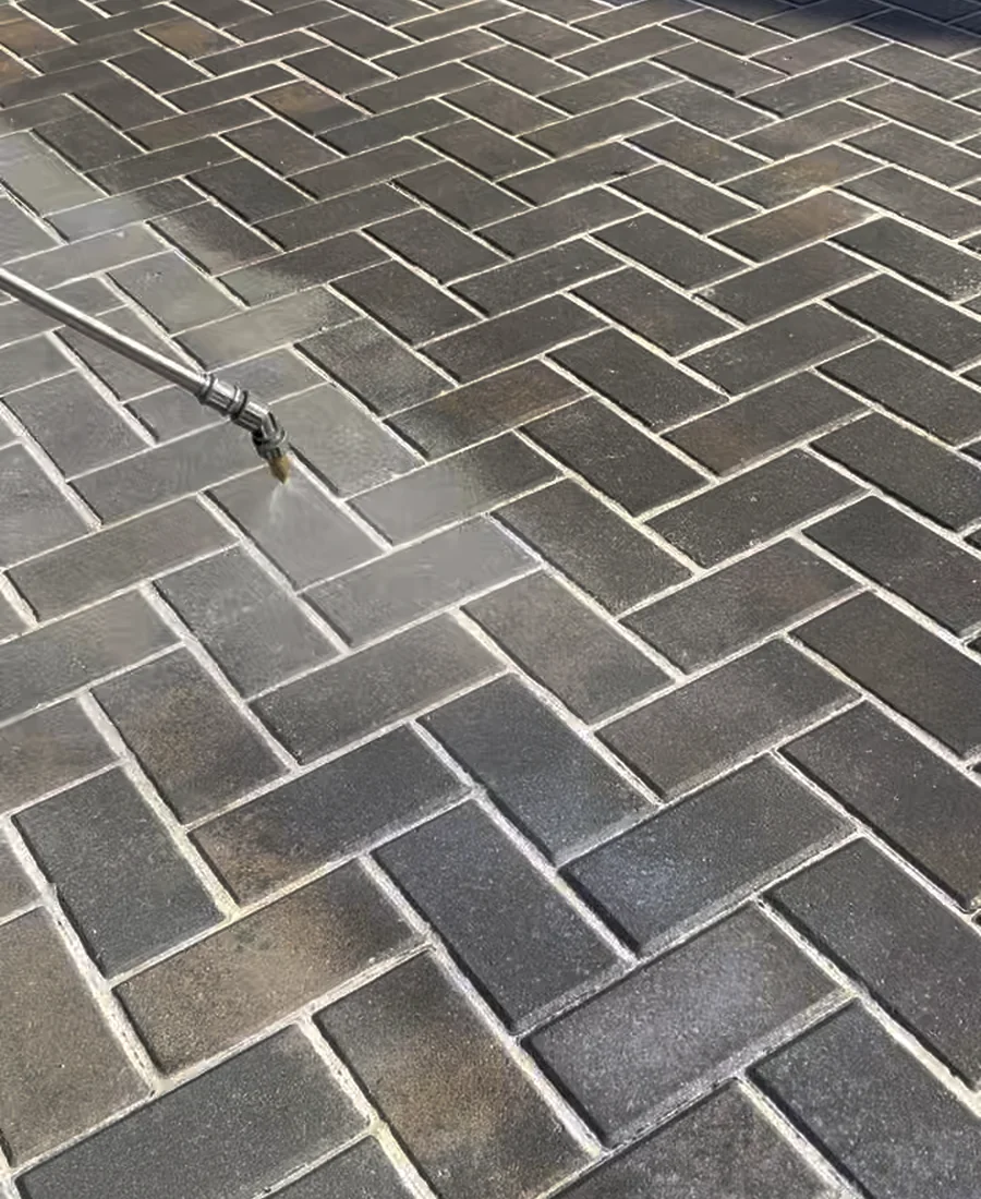 Professional pressure washing wand cleaning a paver driveway